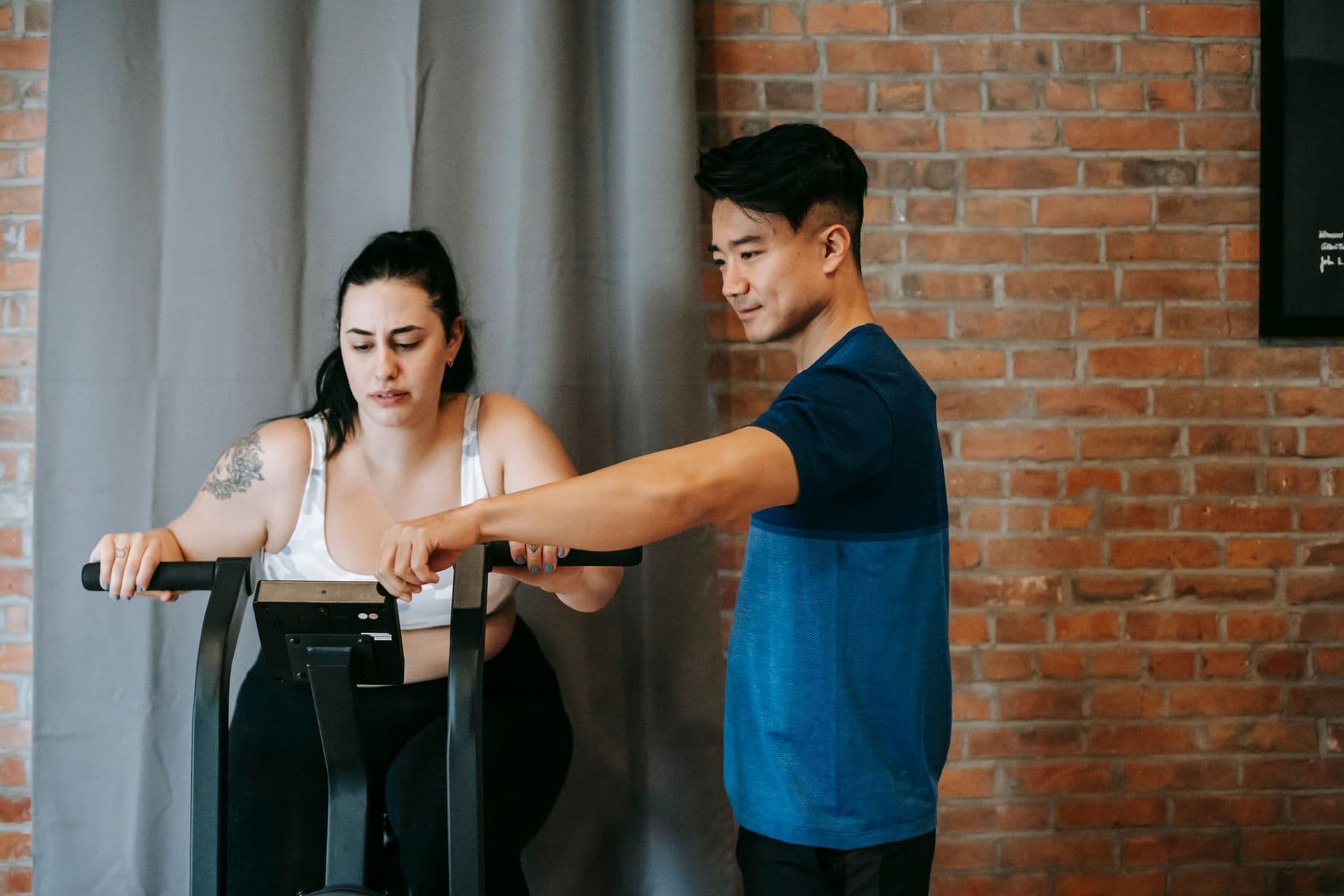 Profissional orientando uma mulher em bicicleta de exercício